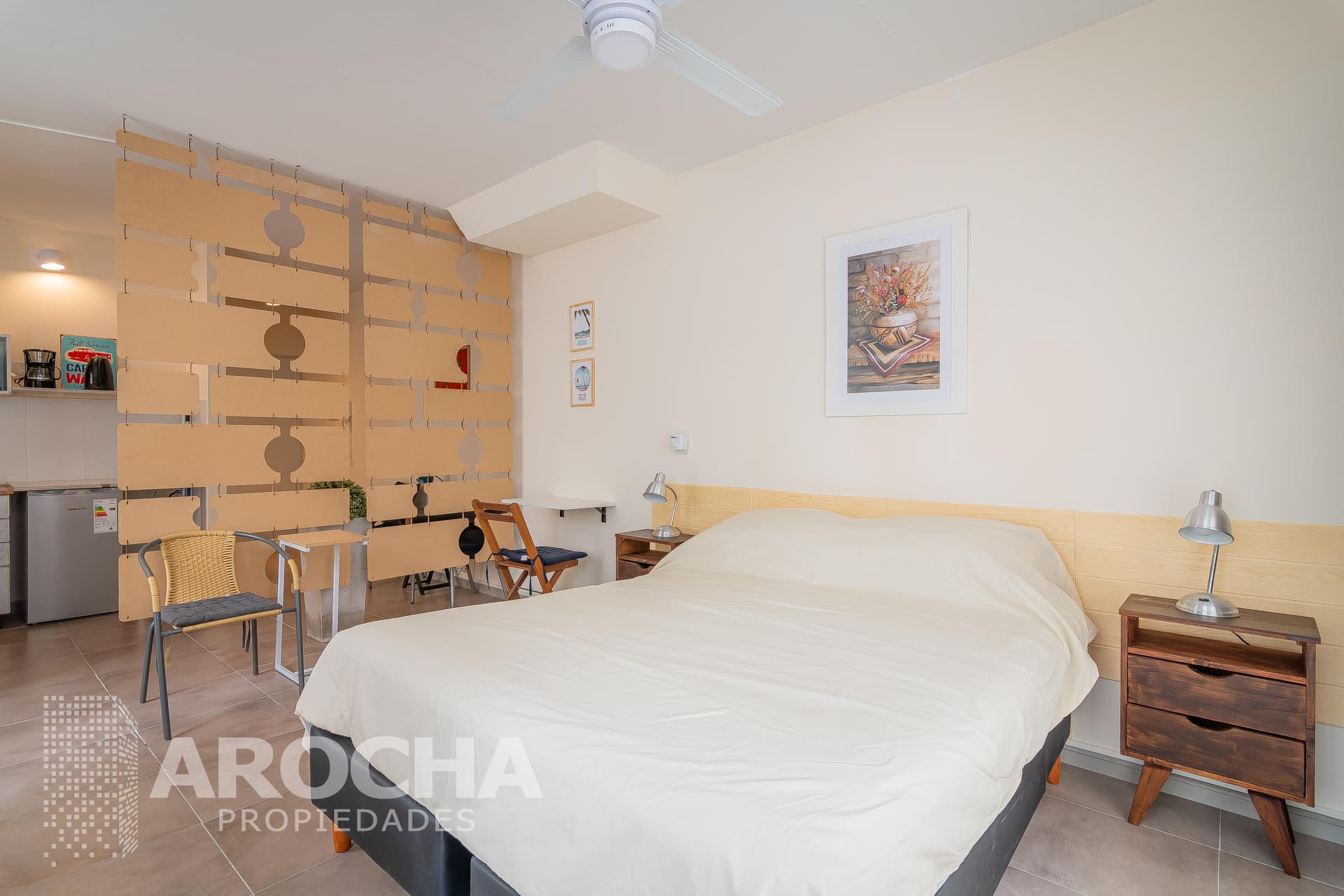 Dormitorio con cama matrimonial, ventilador de techo y separador de ambientes.