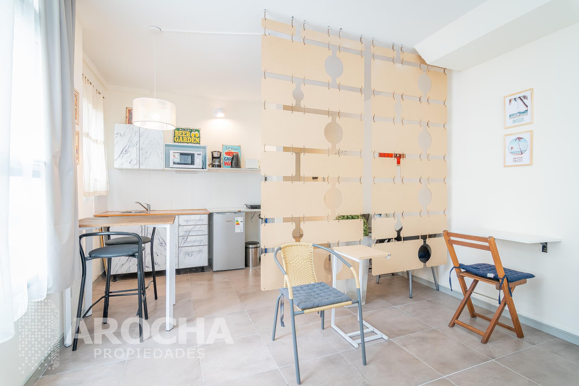 Living con cocina integrada, mesa de comedor y separador de ambientes.