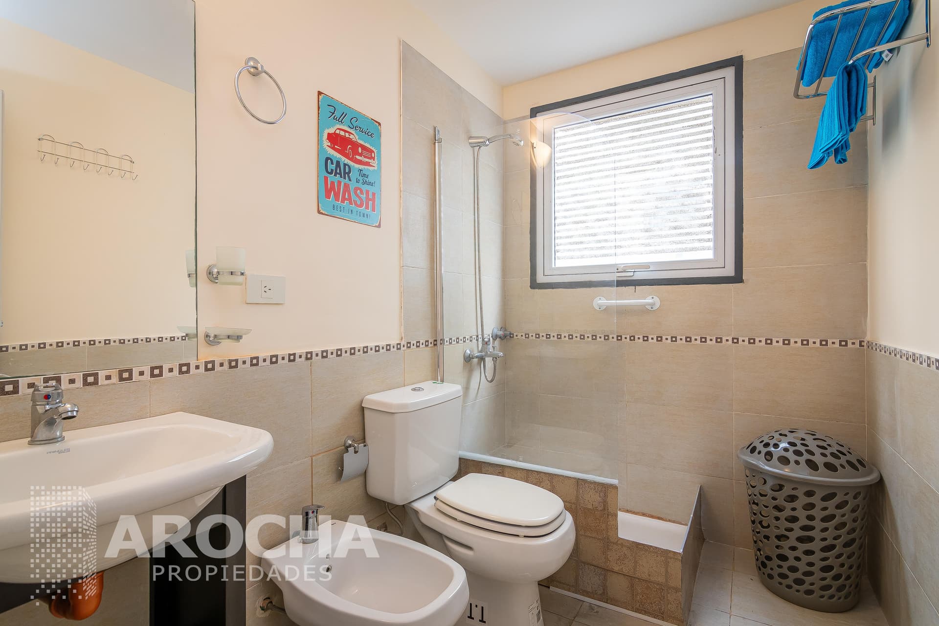 Baño completo con ducha, inodoro, bidet, vanitory y ventana con persiana.