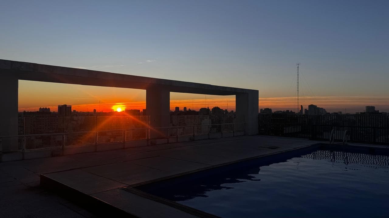 Pileta en la terraza del edificio con vista a la ciudad al atardecer.