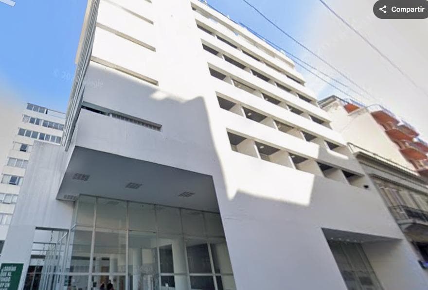 Fachada moderna de edificio blanco con grandes ventanales y entrada.