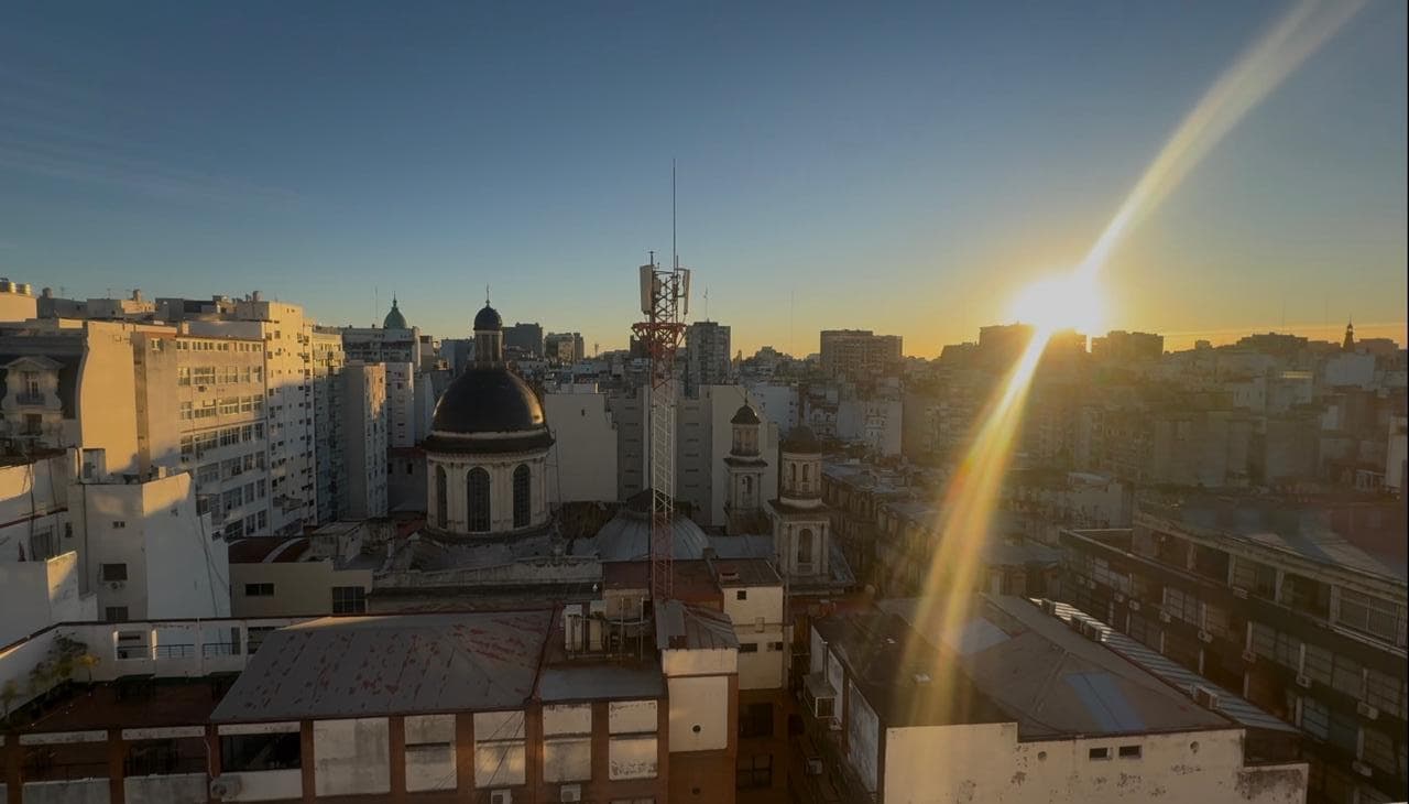Vista de la ciudad al atardecer con cúpulas de edificios y un cielo colorido.