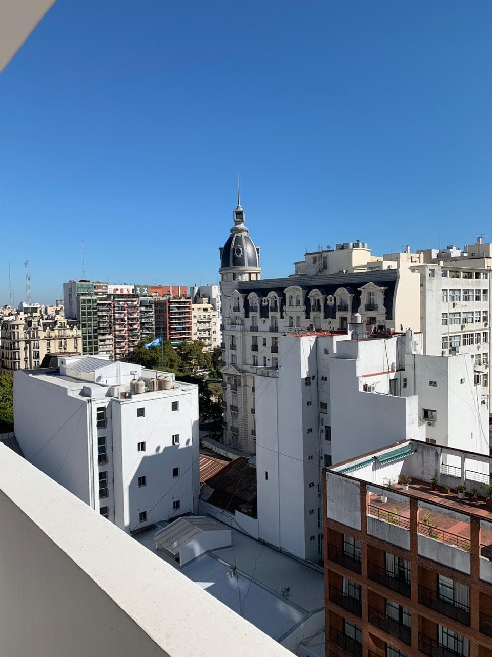 Vista de edificios desde el balcón bajo un cielo azul brillante.