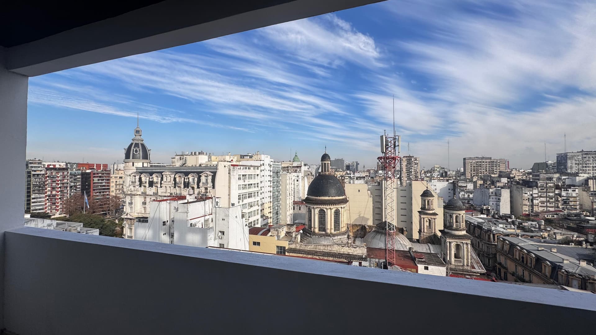 Vista a la ciudad desde el balcón con edificios y un cielo con nubes.