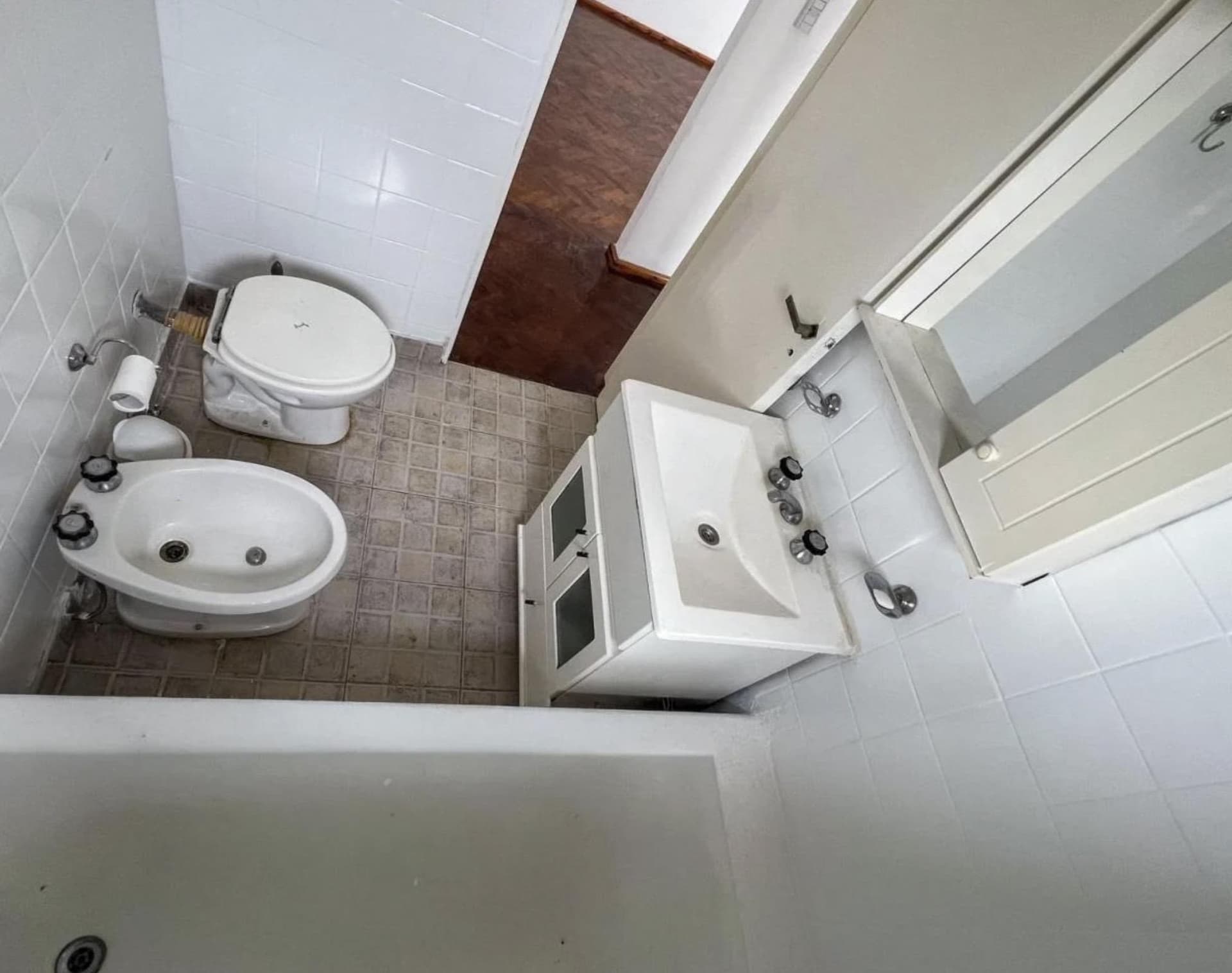 Baño con bidet, inodoro, vanitory blanco y bañera