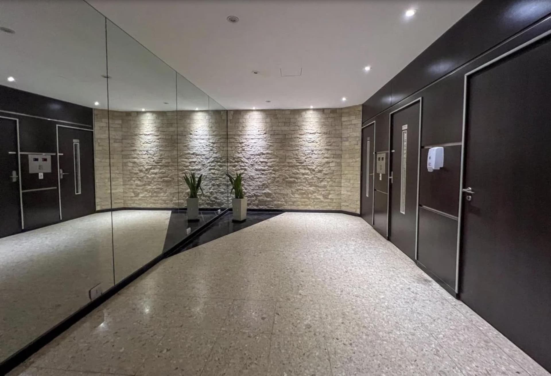 Palier del edificio con pared de piedra y espejos