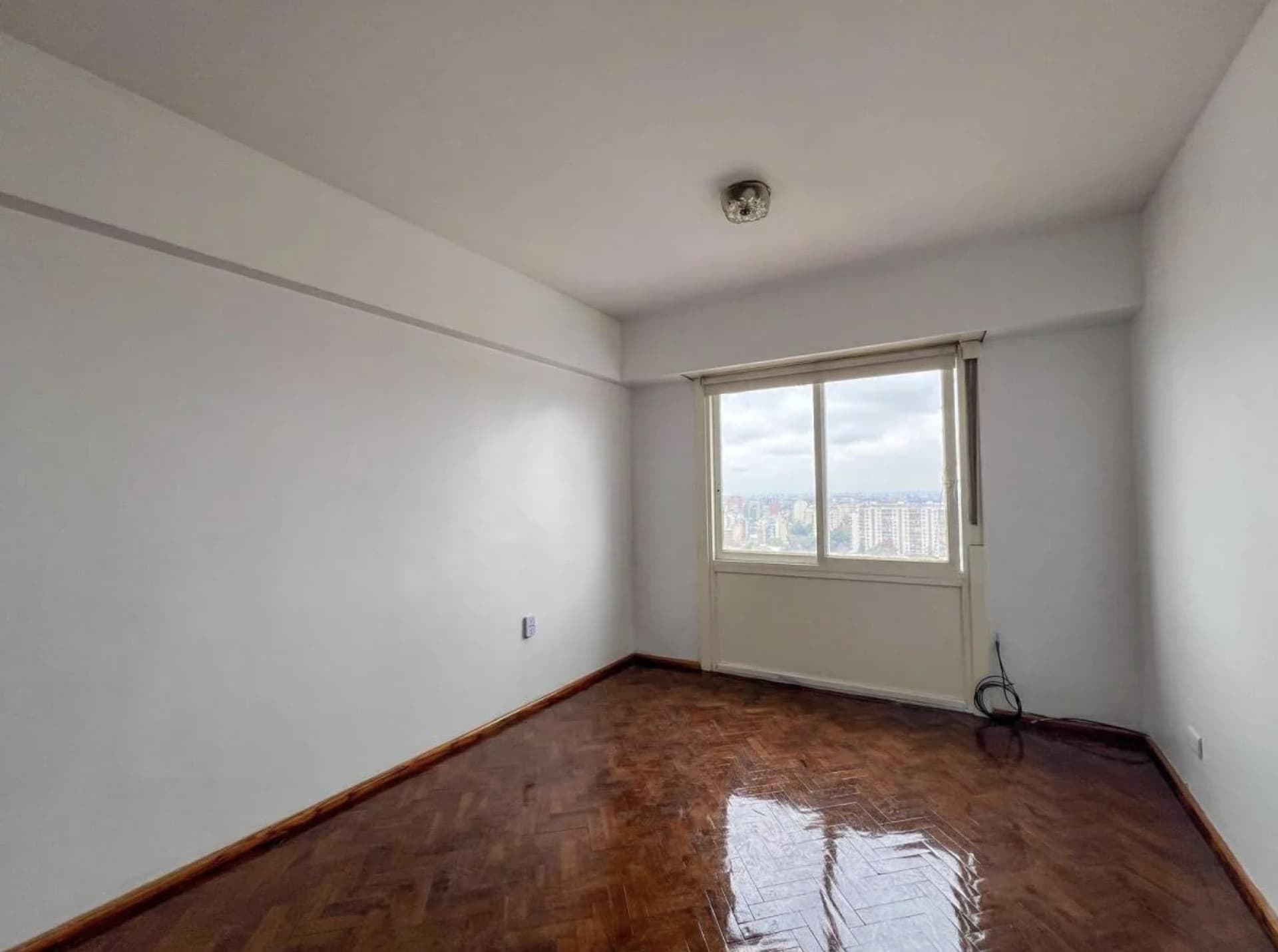 Living vacío con ventana y piso de parquet
