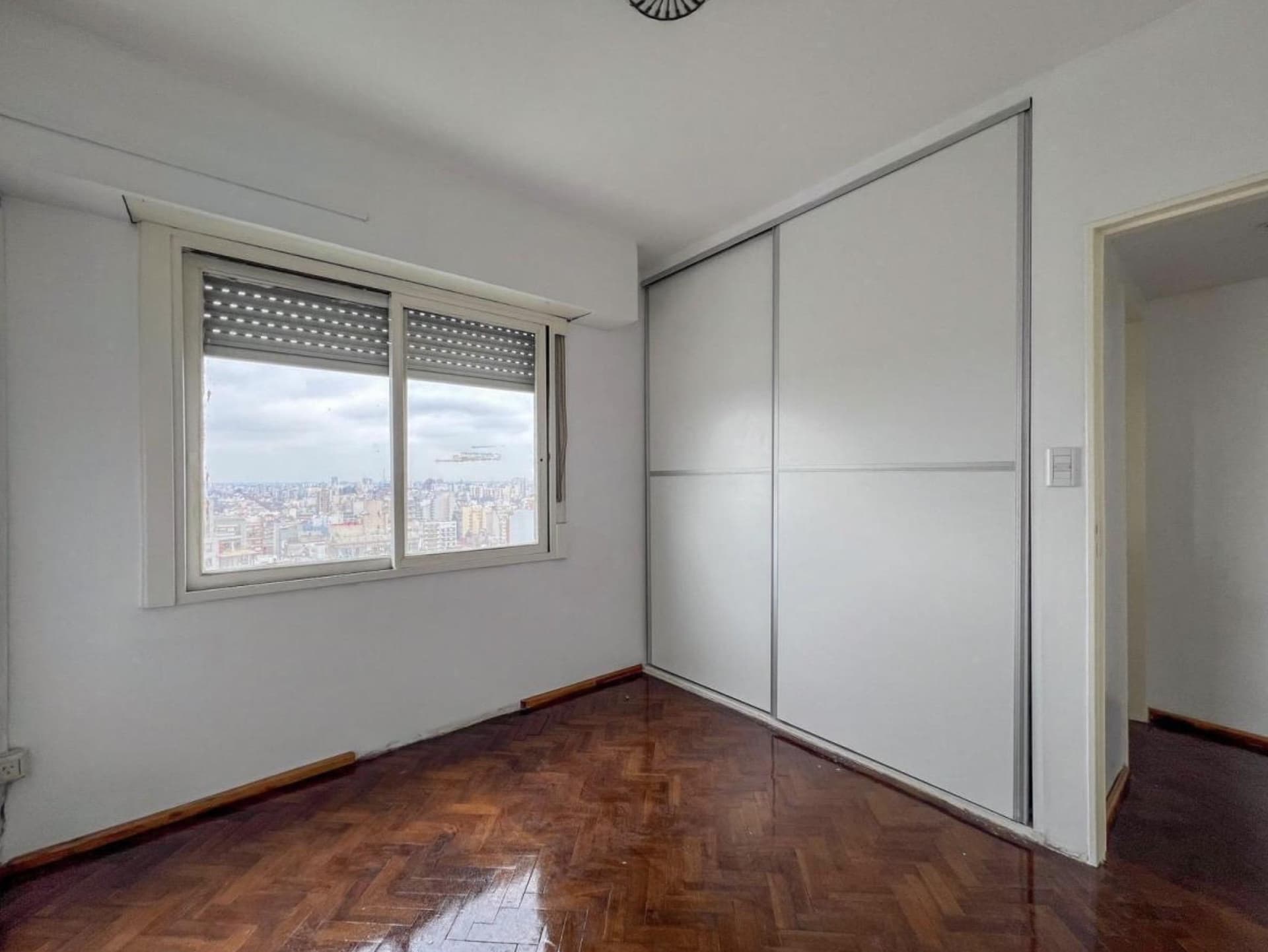 Dormitorio vacío con placard y ventana con vista a la ciudad