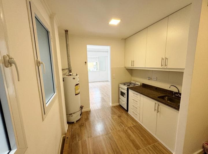 Cocina con mesada, bacha, anafe, alacenas blancas y termotanque.