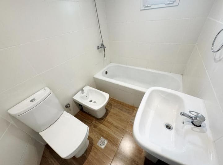 Baño completo con bañera, inodoro, bidet, lavatorio y azulejos blancos.