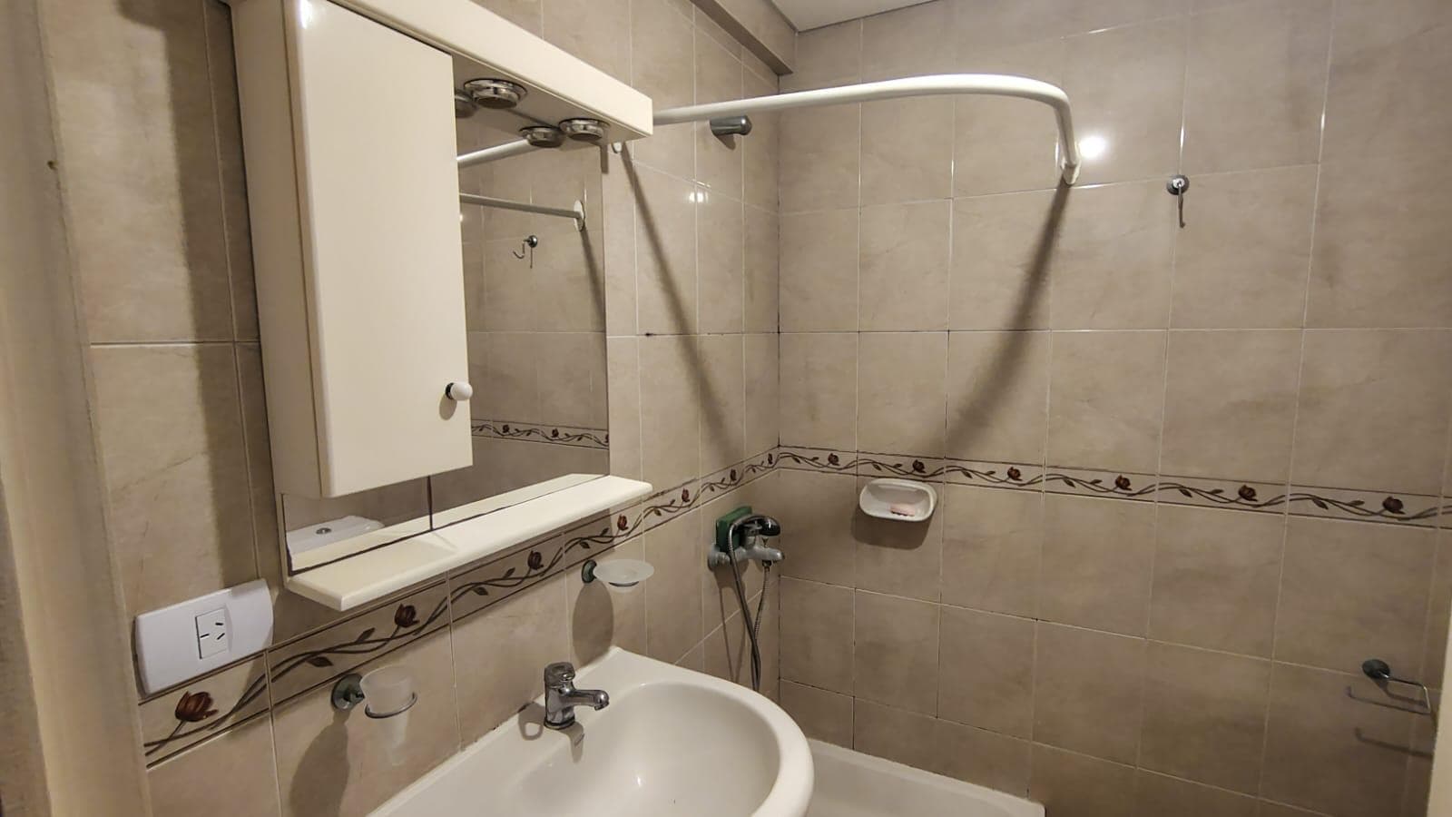Baño con vanitory, espejo, y caño para cortina de ducha.