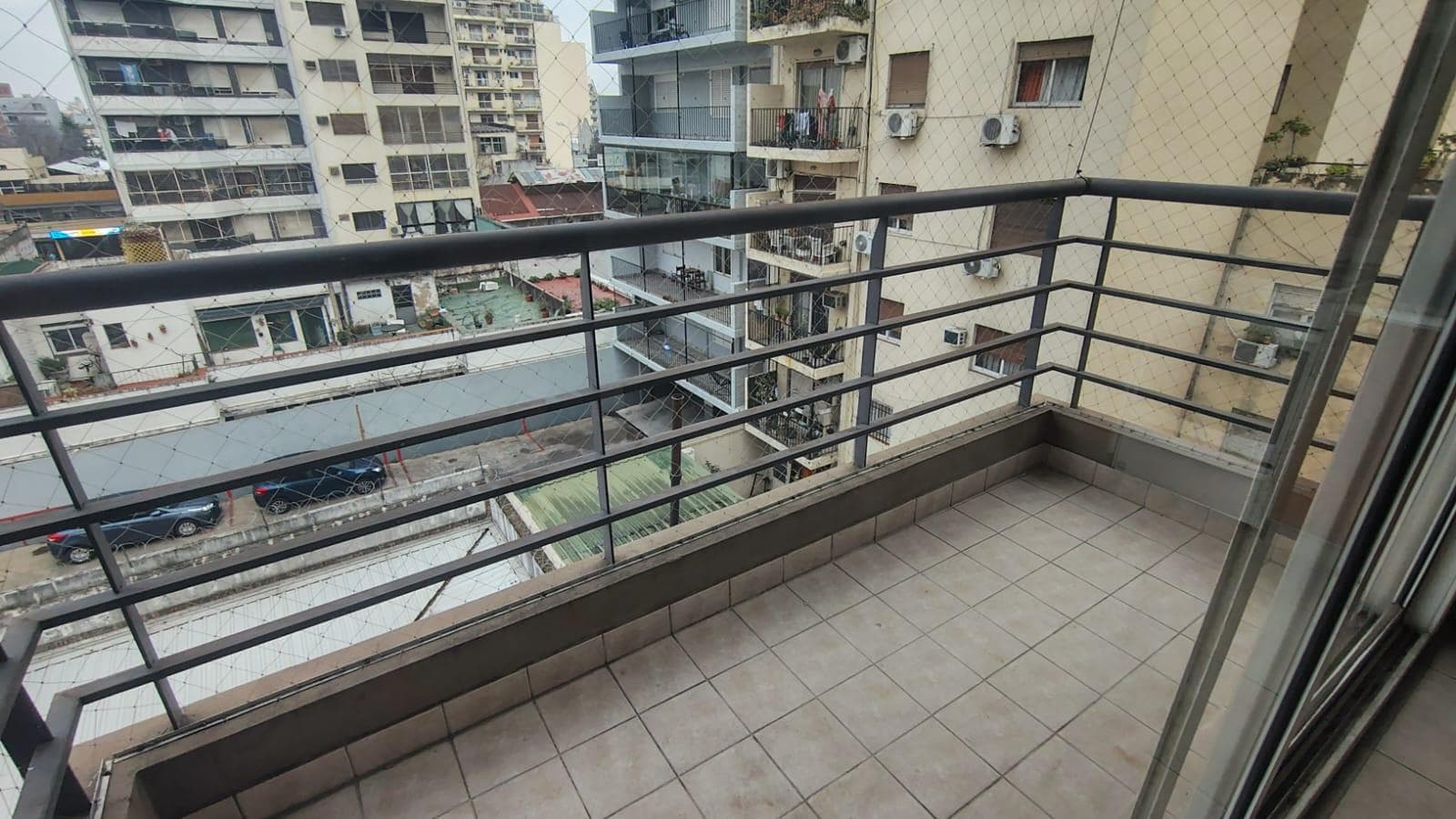 Balcón con rejas de seguridad, vista a edificios y calle de la ciudad.