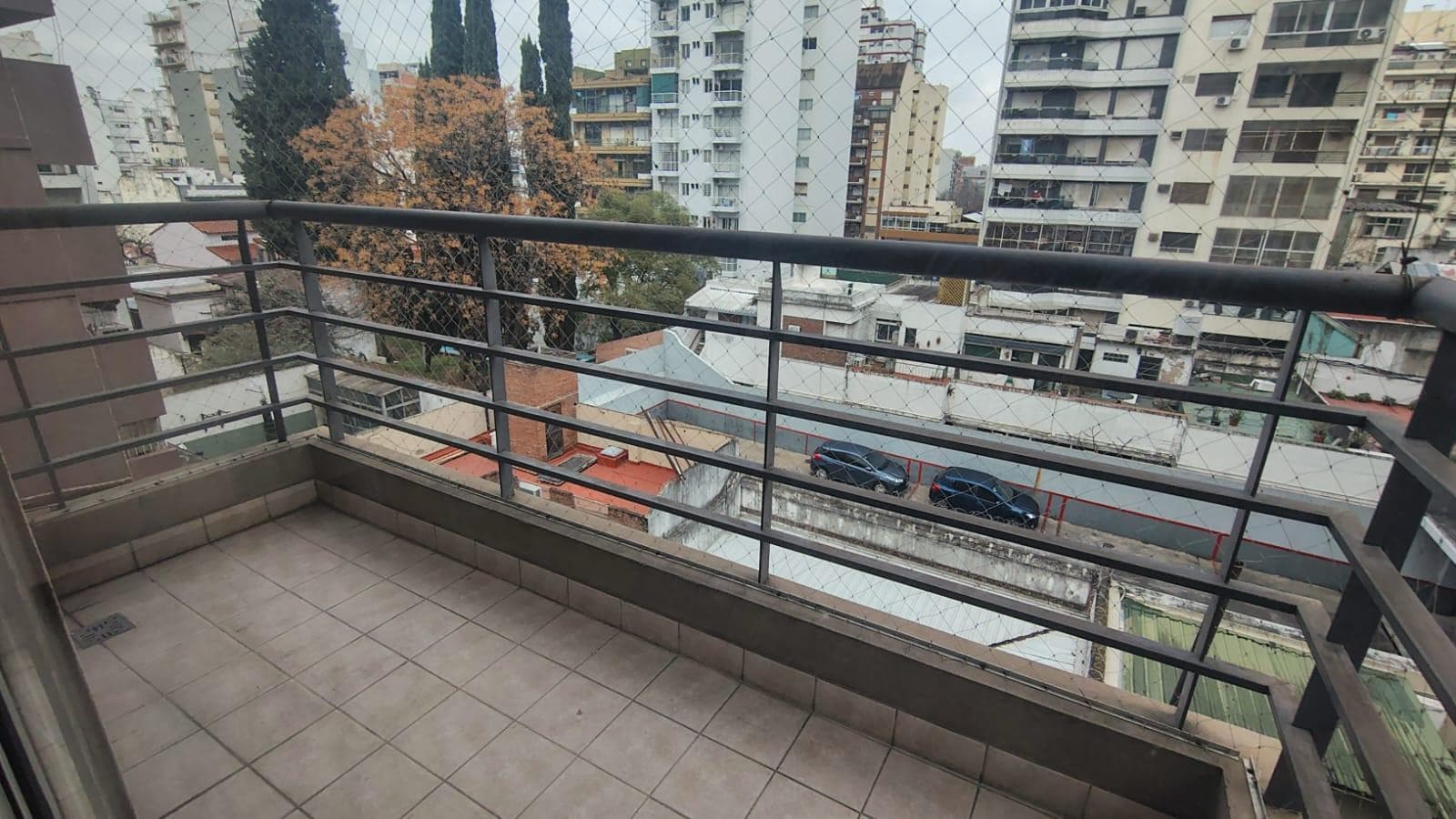 Balcón amplio con rejas, con vista panorámica a la ciudad y edificios.