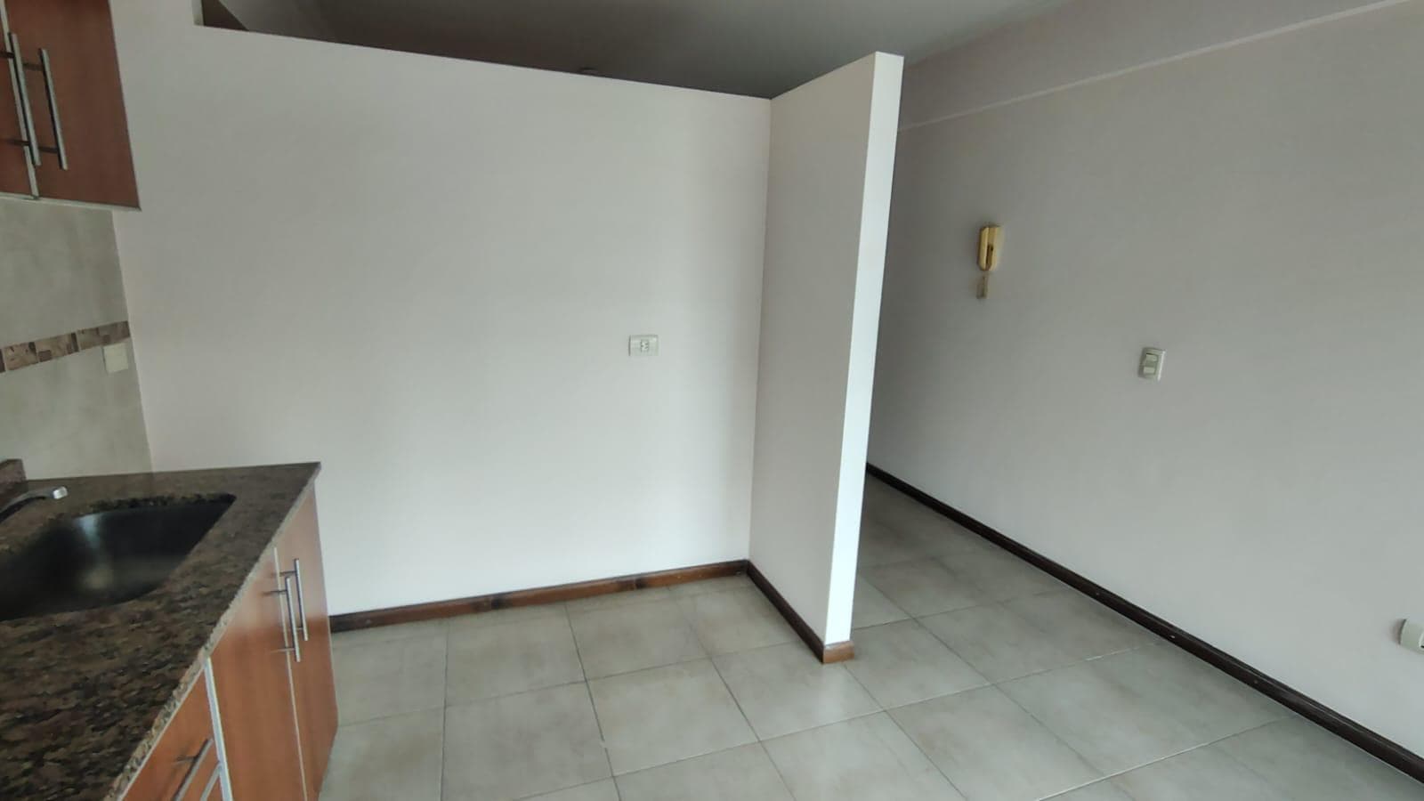 Cocina integrada con mesada, alacenas, y espacio de living con pasillo.