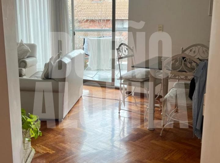 Living comedor con sillón, mesa y sillas, acceso a balcón.