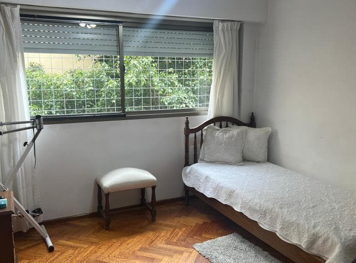Dormitorio secundario con cama individual y ventana al exterior.