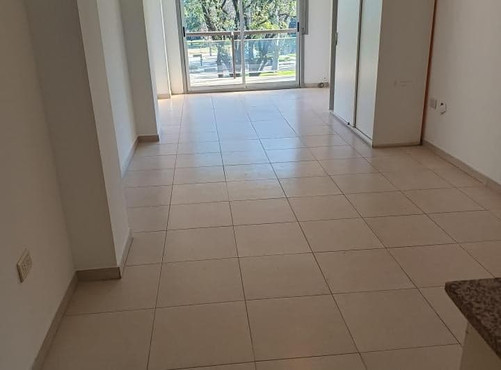 Living vacío con piso cerámico, puerta balcón y armario.