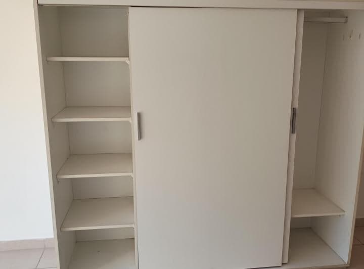 Interior de un placard blanco con estantes y barral.