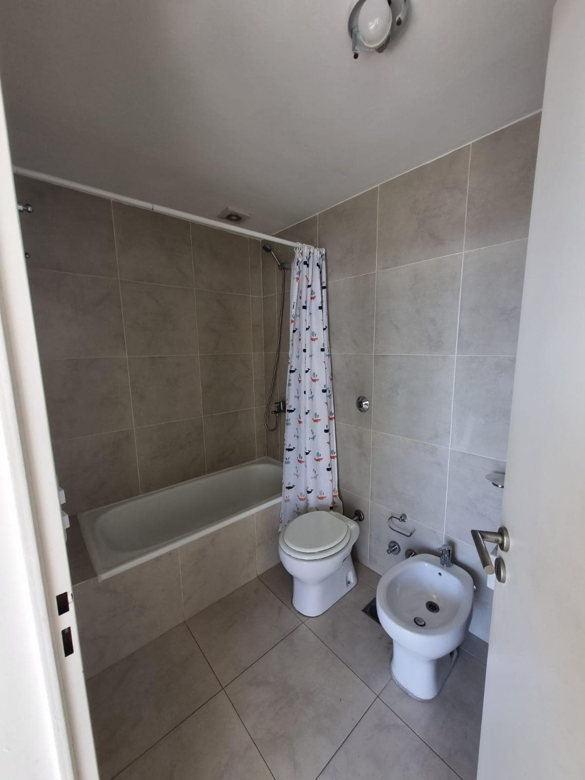Baño con bañera, inodoro, bidet y cortina de baño.
