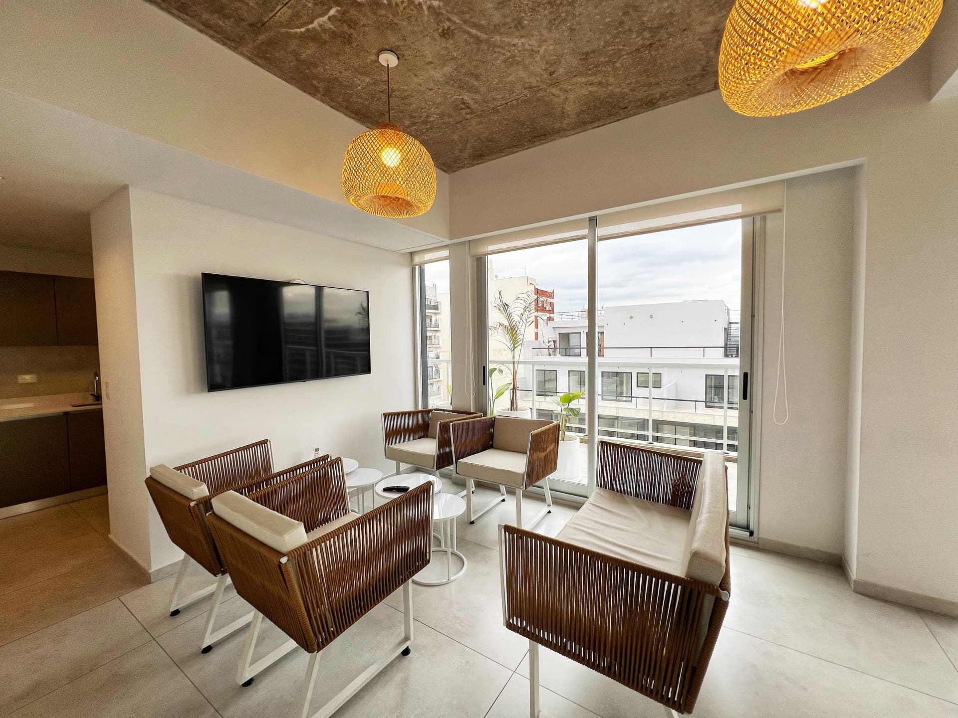 Living del SUM con sillones modernos, televisor y grandes ventanales con vista.