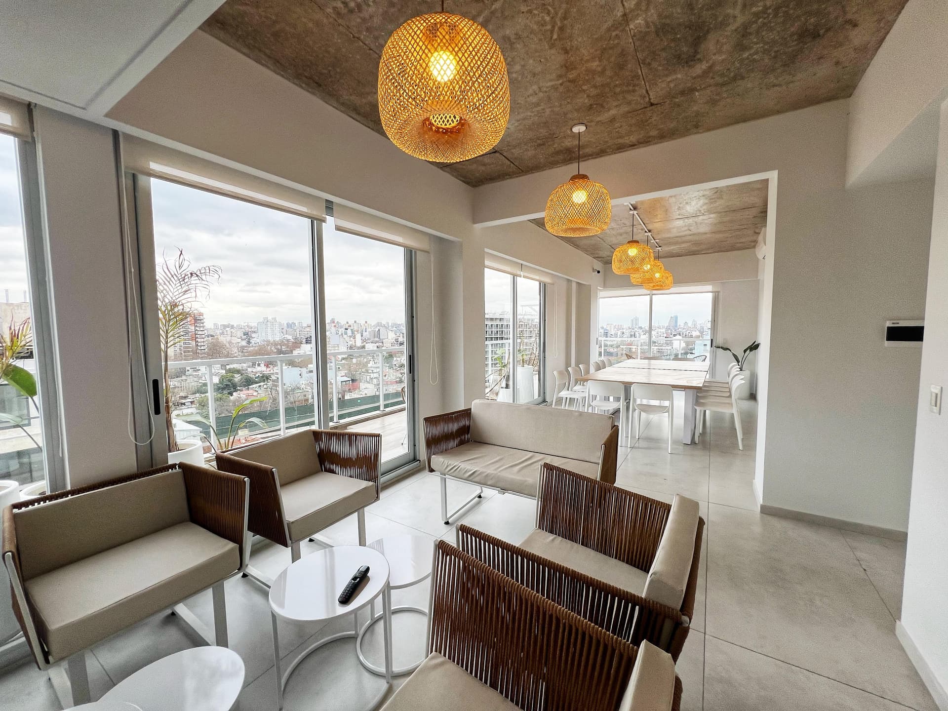 Living comedor del SUM con sillones, mesa grande y vista panorámica a la ciudad.