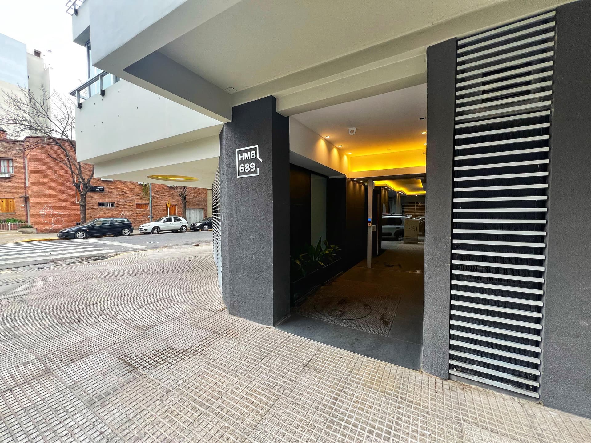 Fachada del edificio con entrada principal a pie de calle y vereda.