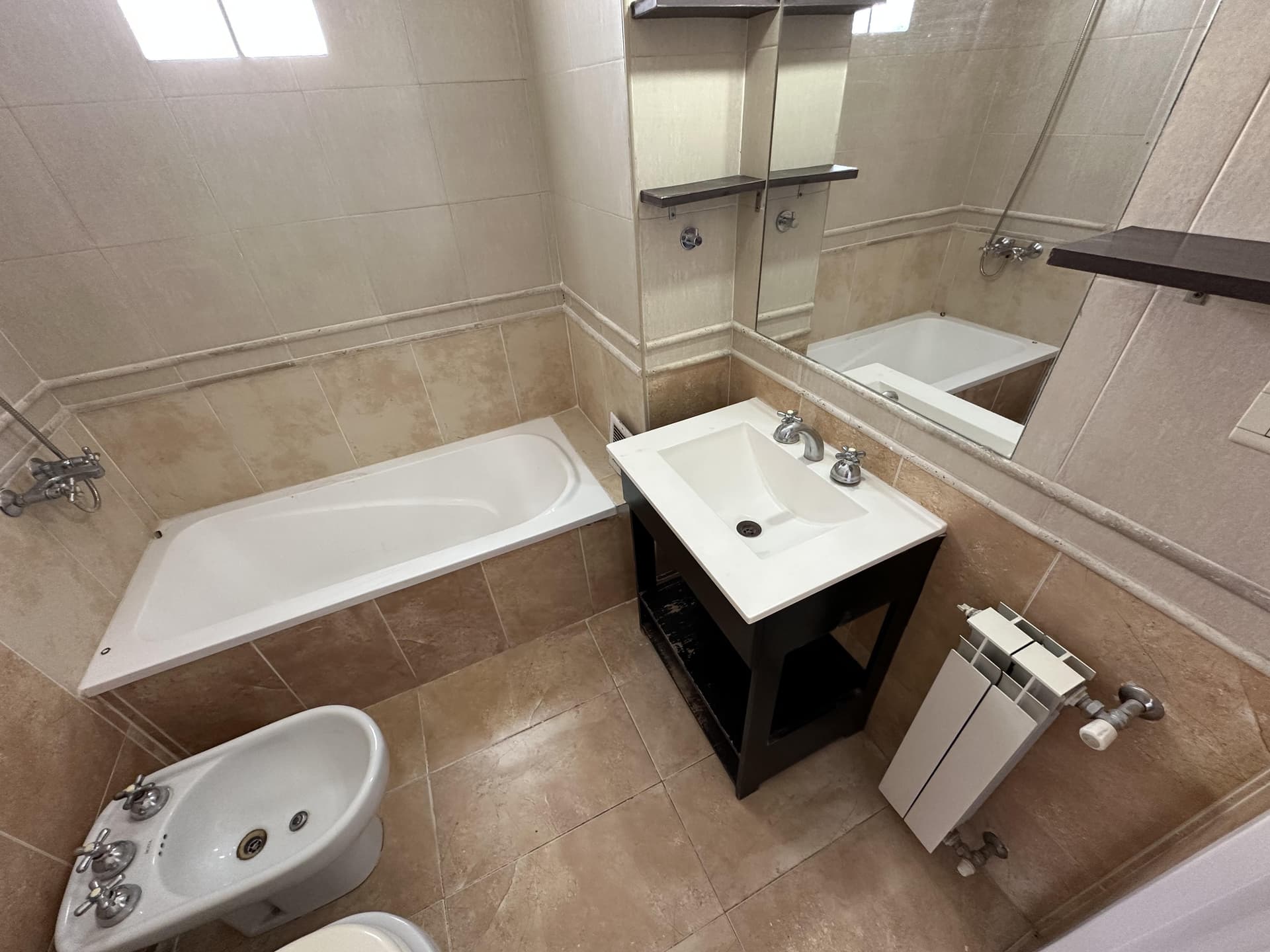 Baño completo con bañera, inodoro, bidet, vanitory y radiador.
