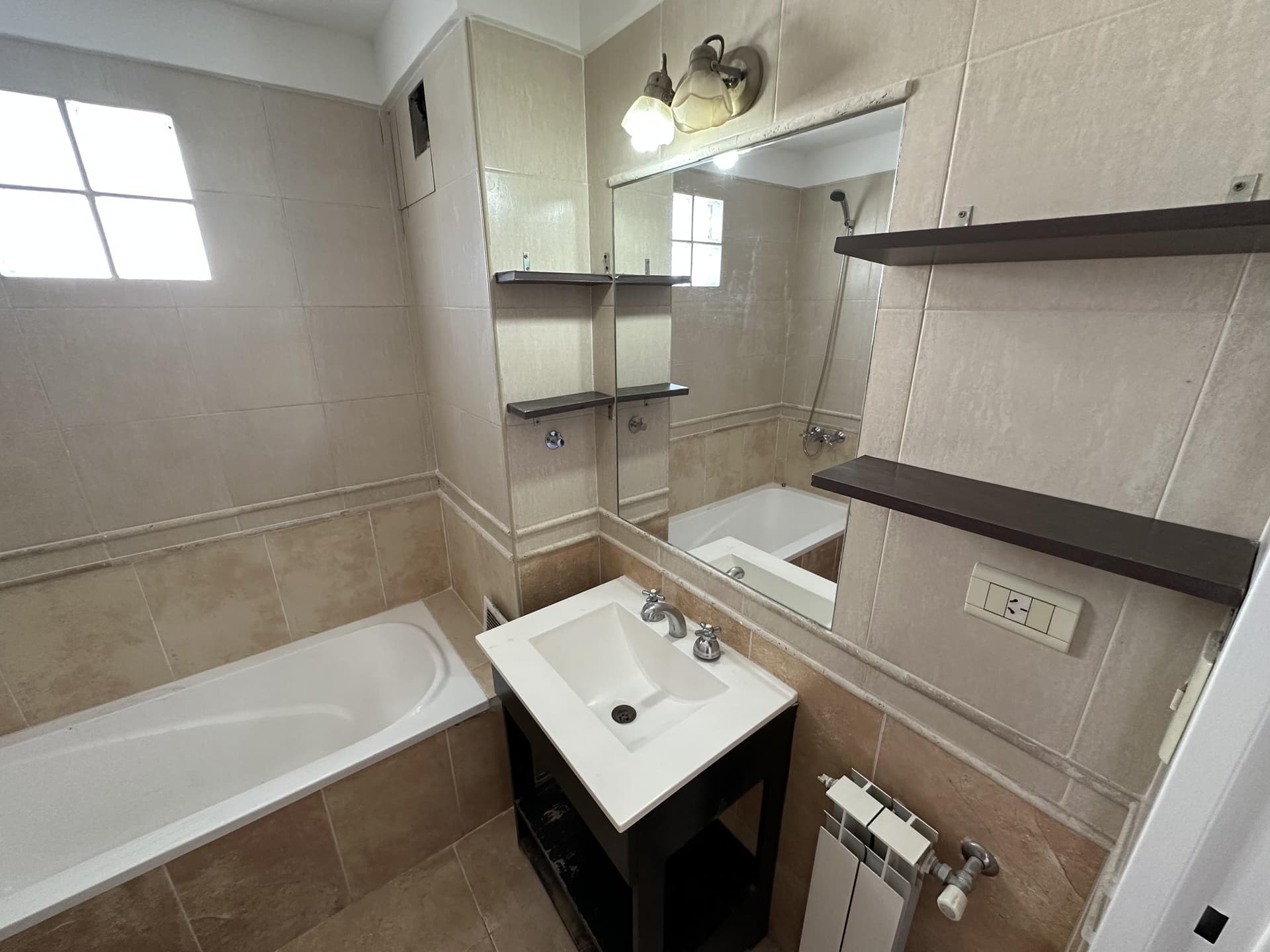 Baño con bañera, vanitory y espejo grande, con iluminación.