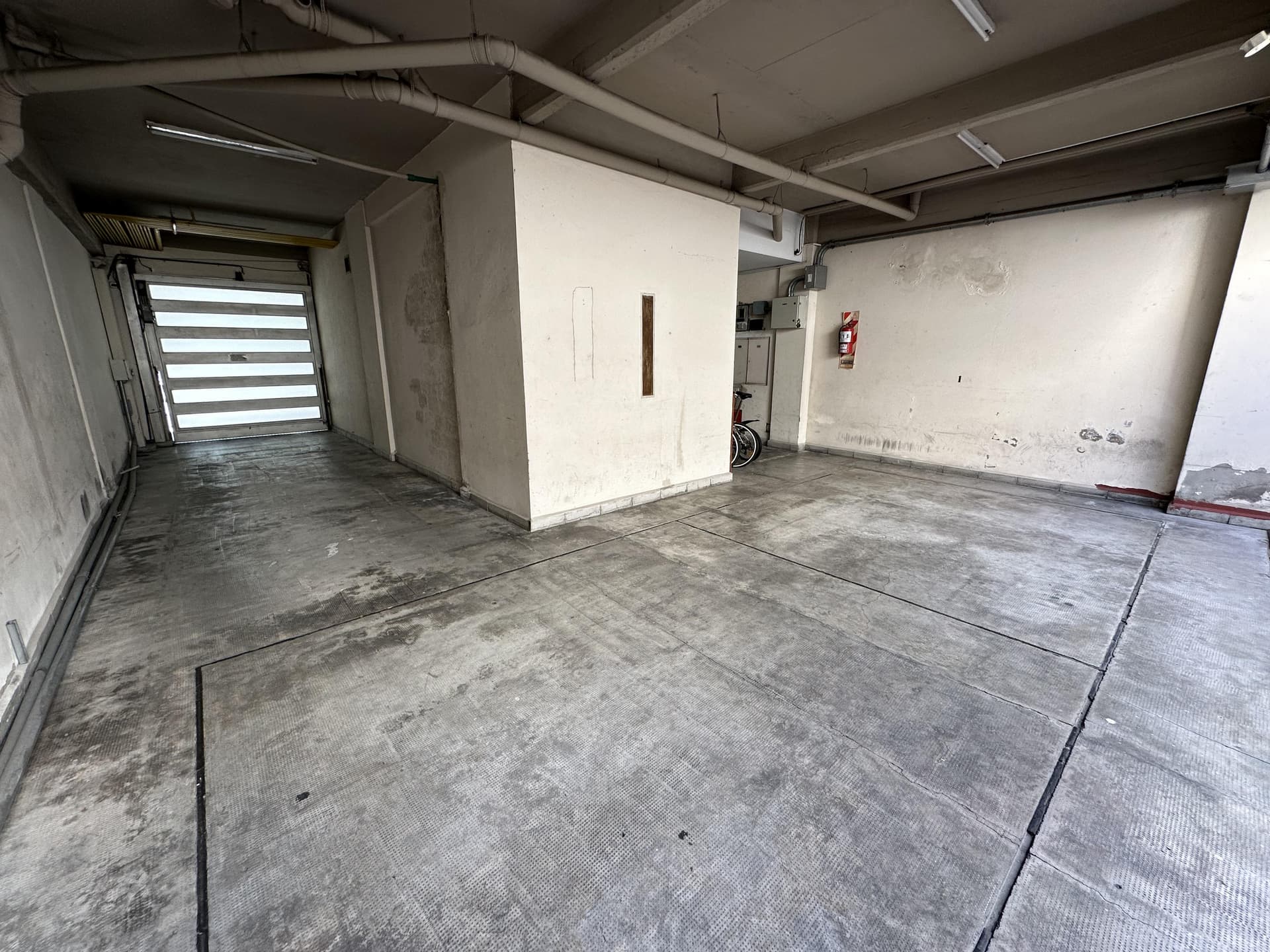 Cochera subterránea con portón automático y piso de cemento.