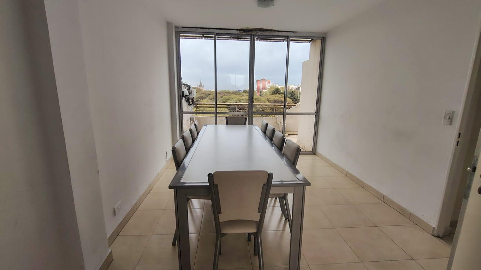 SUM con mesa larga, sillas y ventanal, con vista exterior.