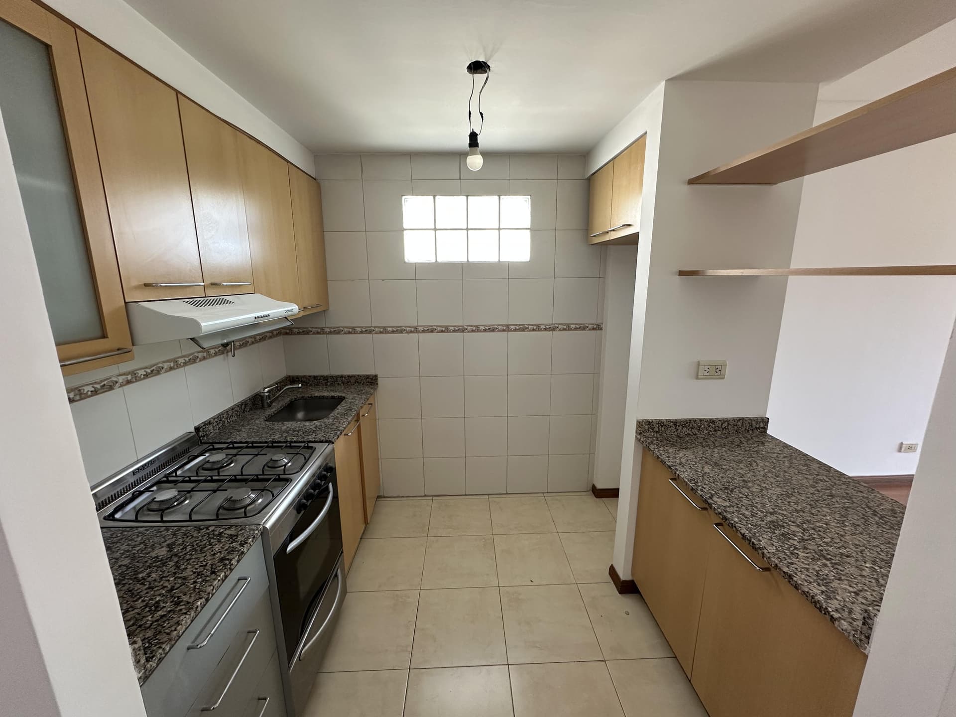 Cocina con mesada, bacha, anafe/horno y alacenas de madera.