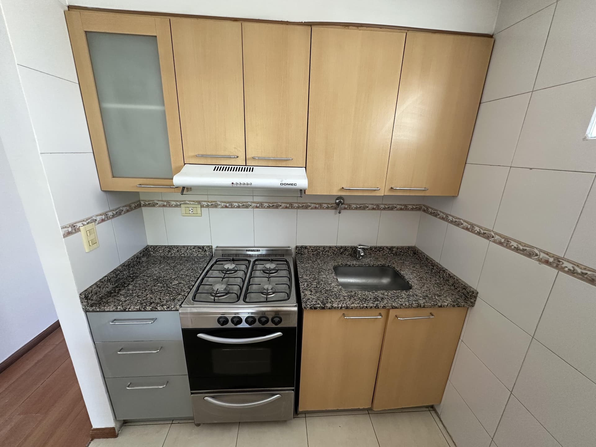 Cocina con mesada de granito, bacha, anafe/horno y alacenas.