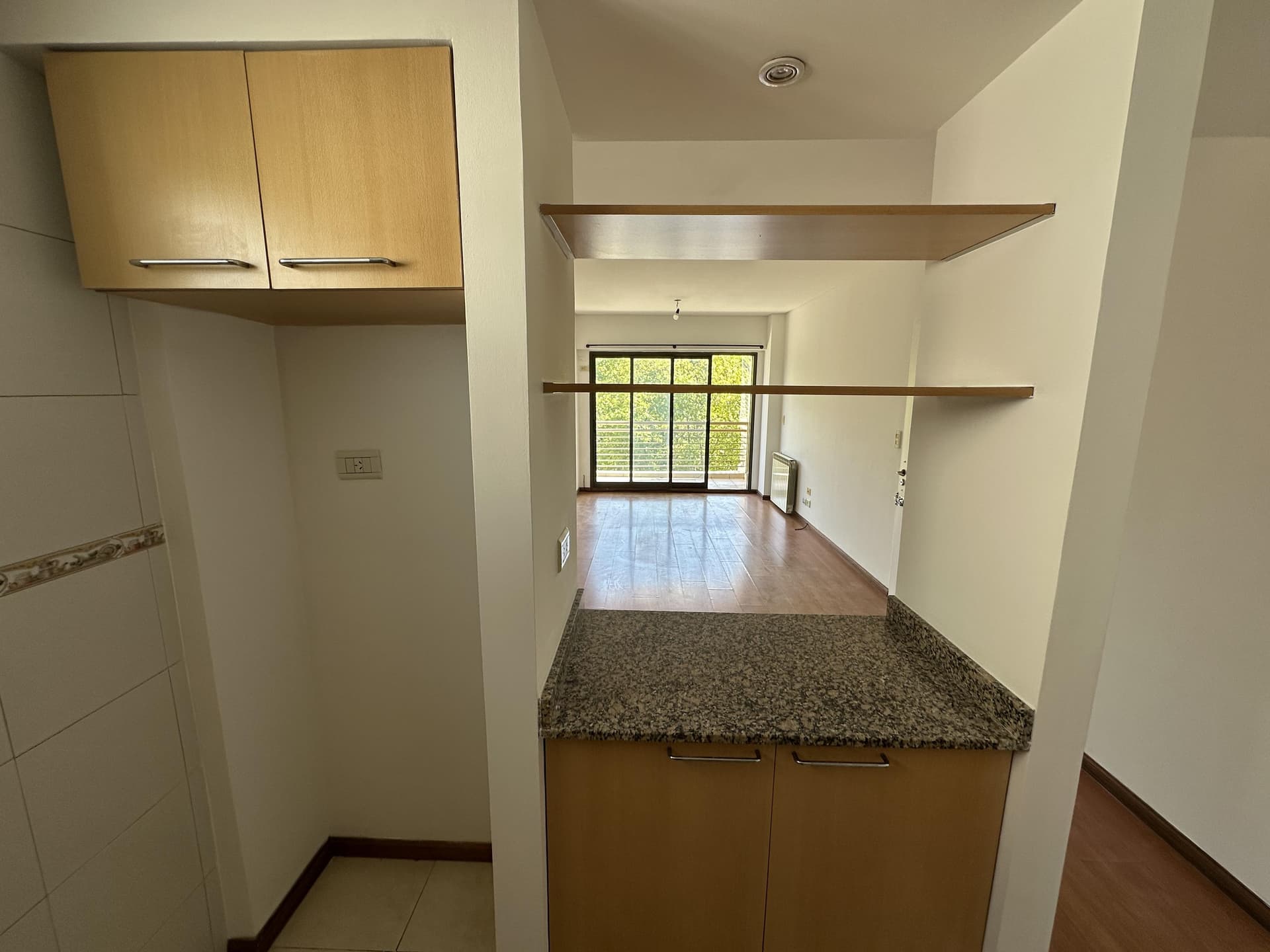 Cocina con barra divisoria hacia el living, mesada y estantes.