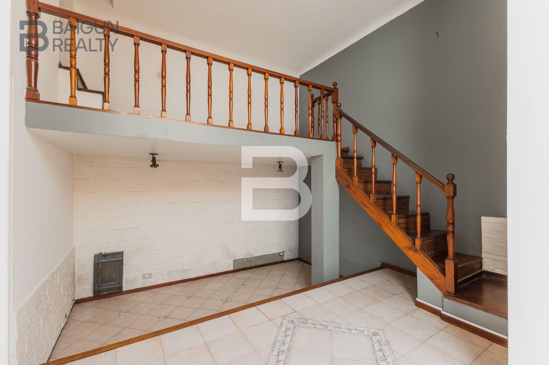 Living con escalera de madera y paredes grises.