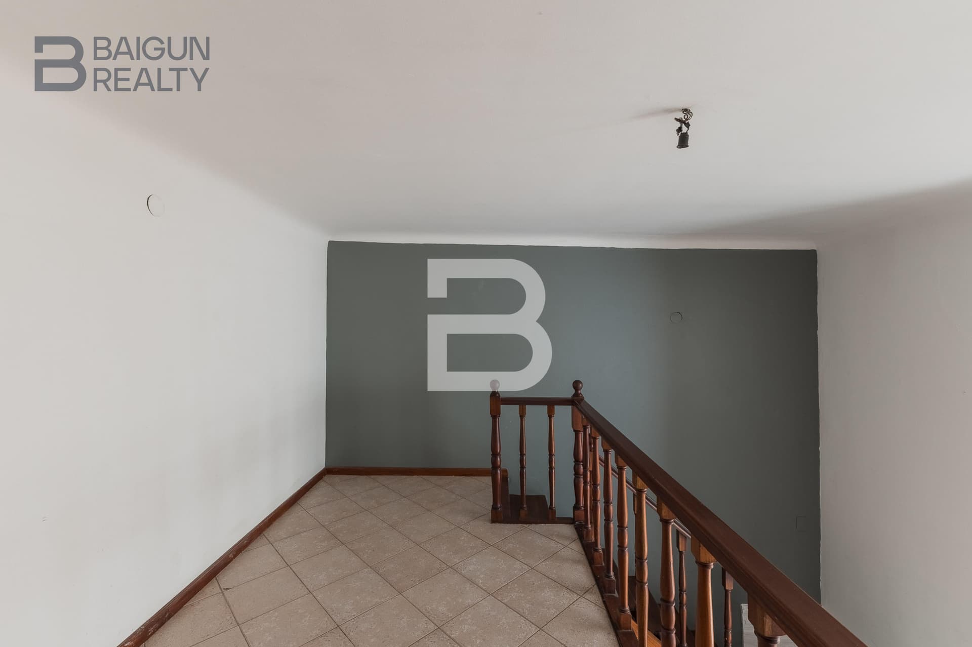 Pasillo superior con balcón y pared gris.