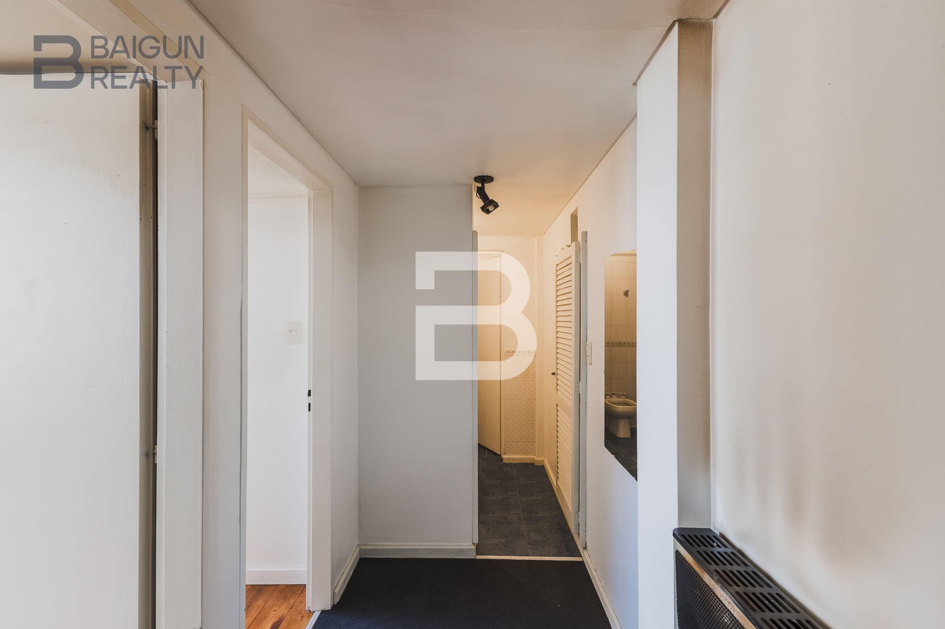 Pasillo distribuidor con espejo y puerta al baño.