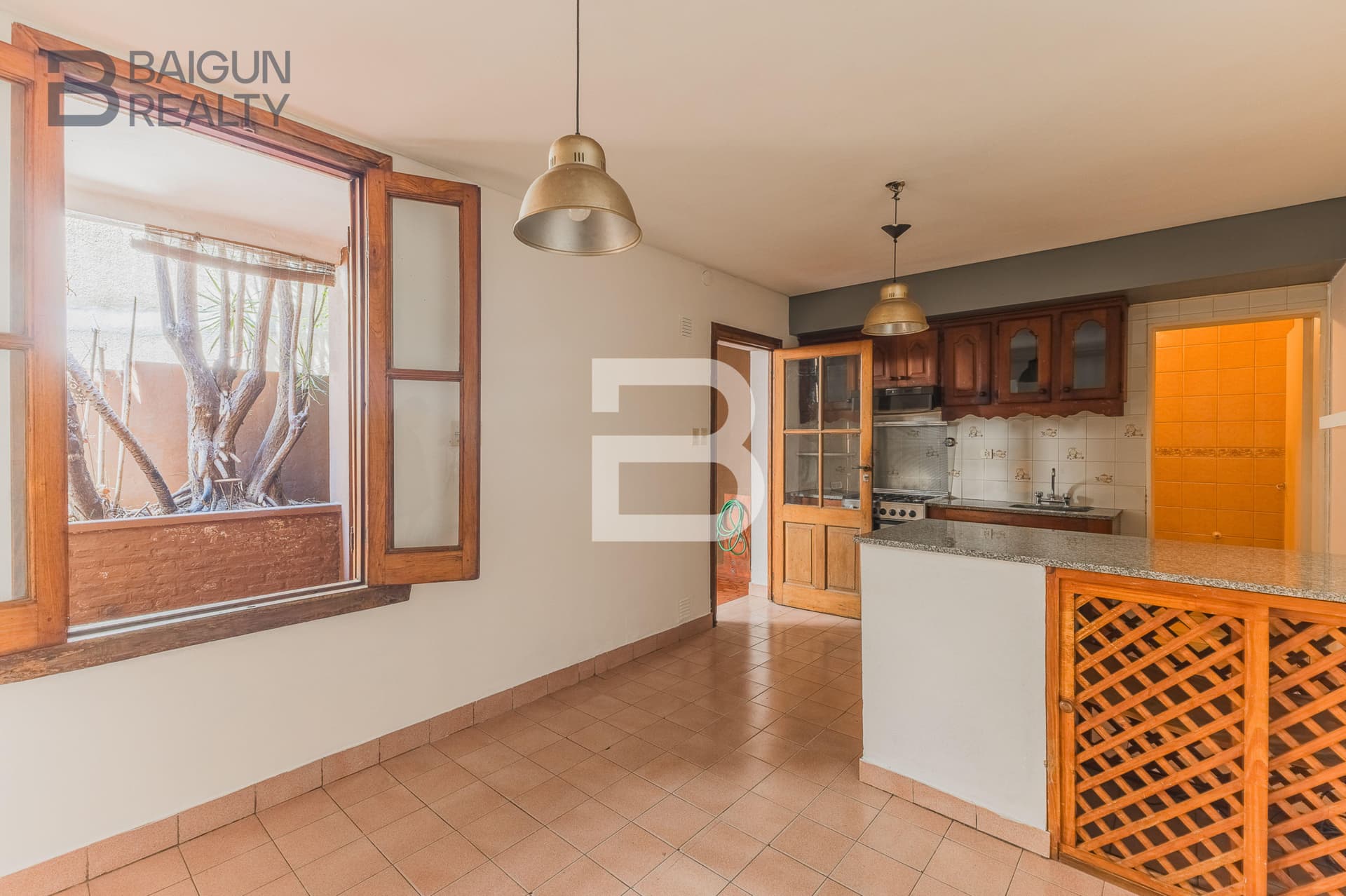 Cocina con barra, muebles de madera y ventana.