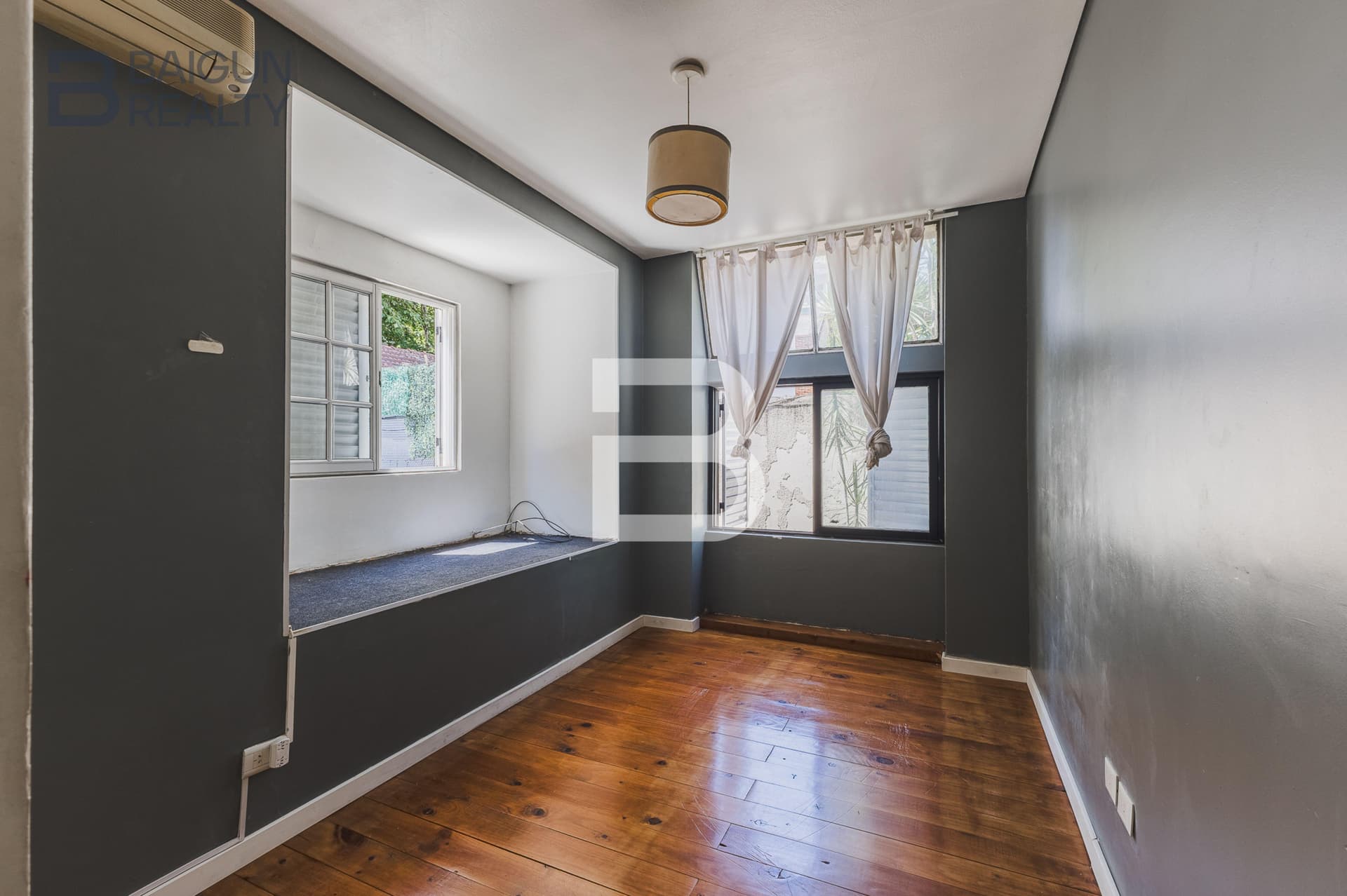 Dormitorio vacío con ventanas y piso de madera.