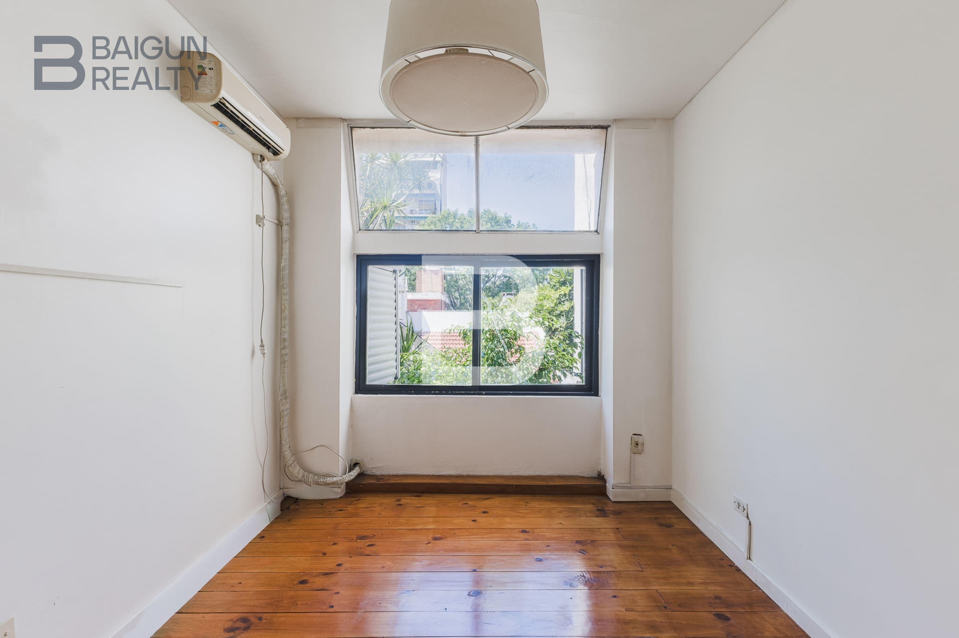Dormitorio vacío con ventana y aire acondicionado.