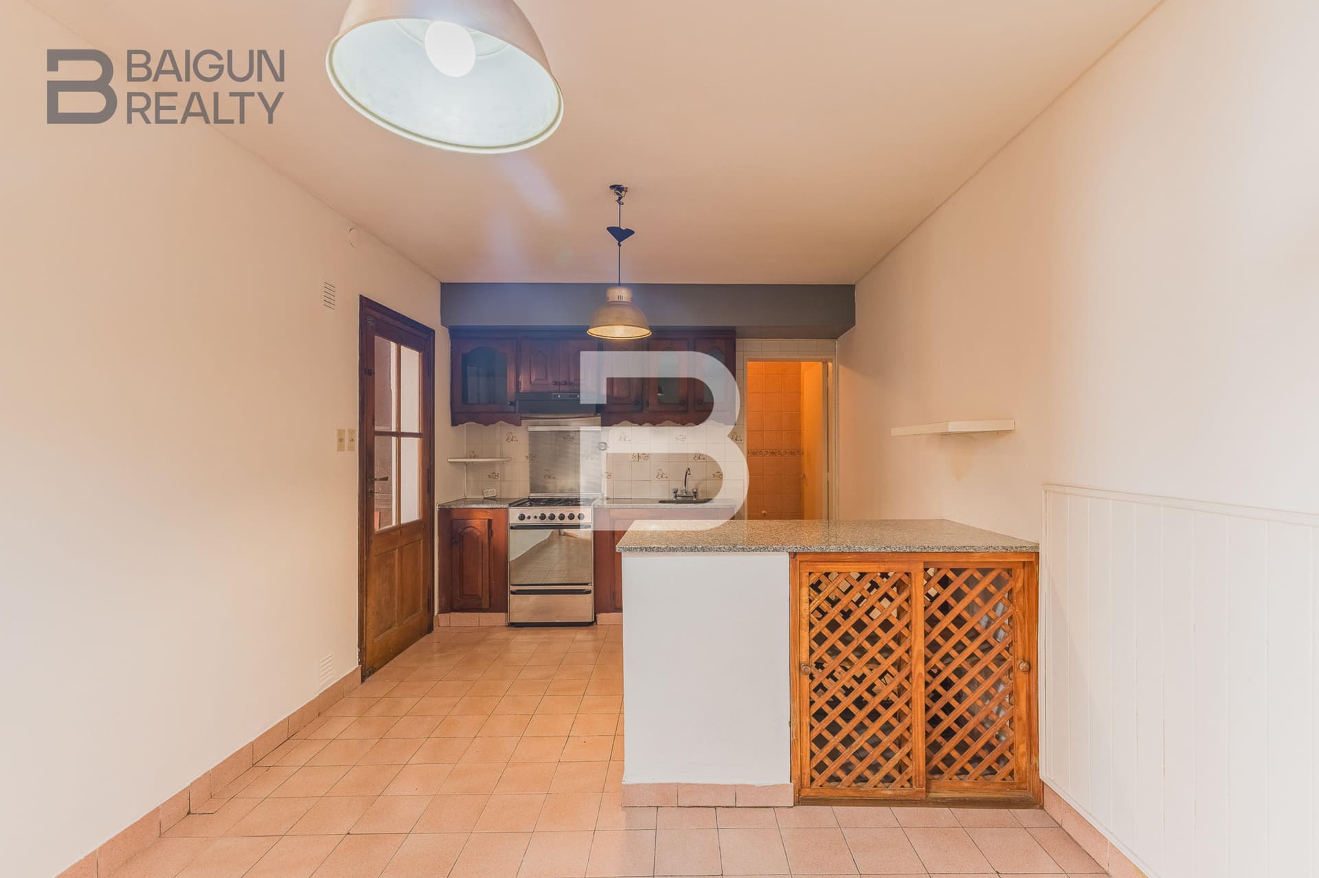 Cocina integrada con horno, alacenas de madera y barra.