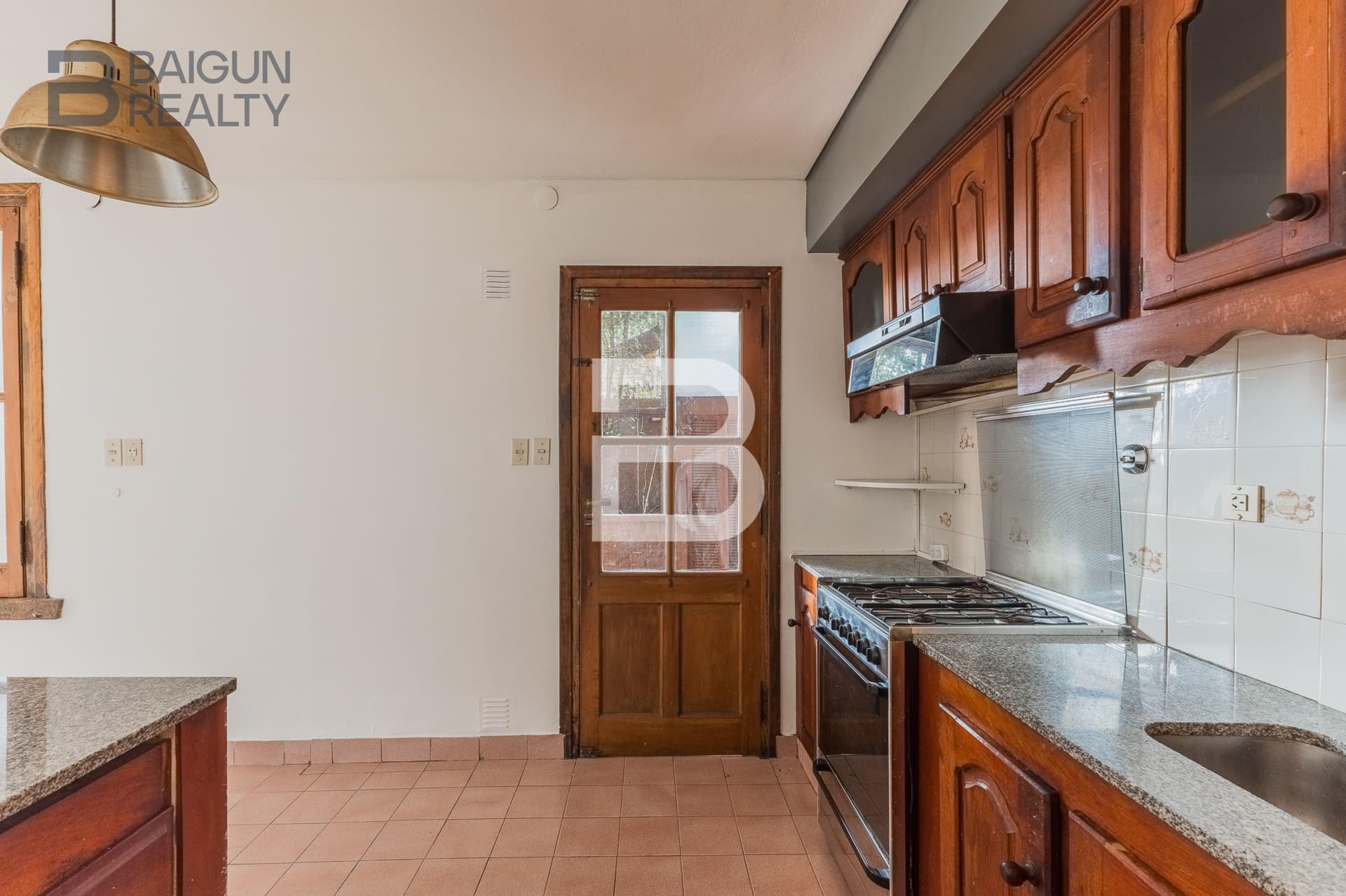 Cocina con anafe, mesada de granito y alacenas de madera.