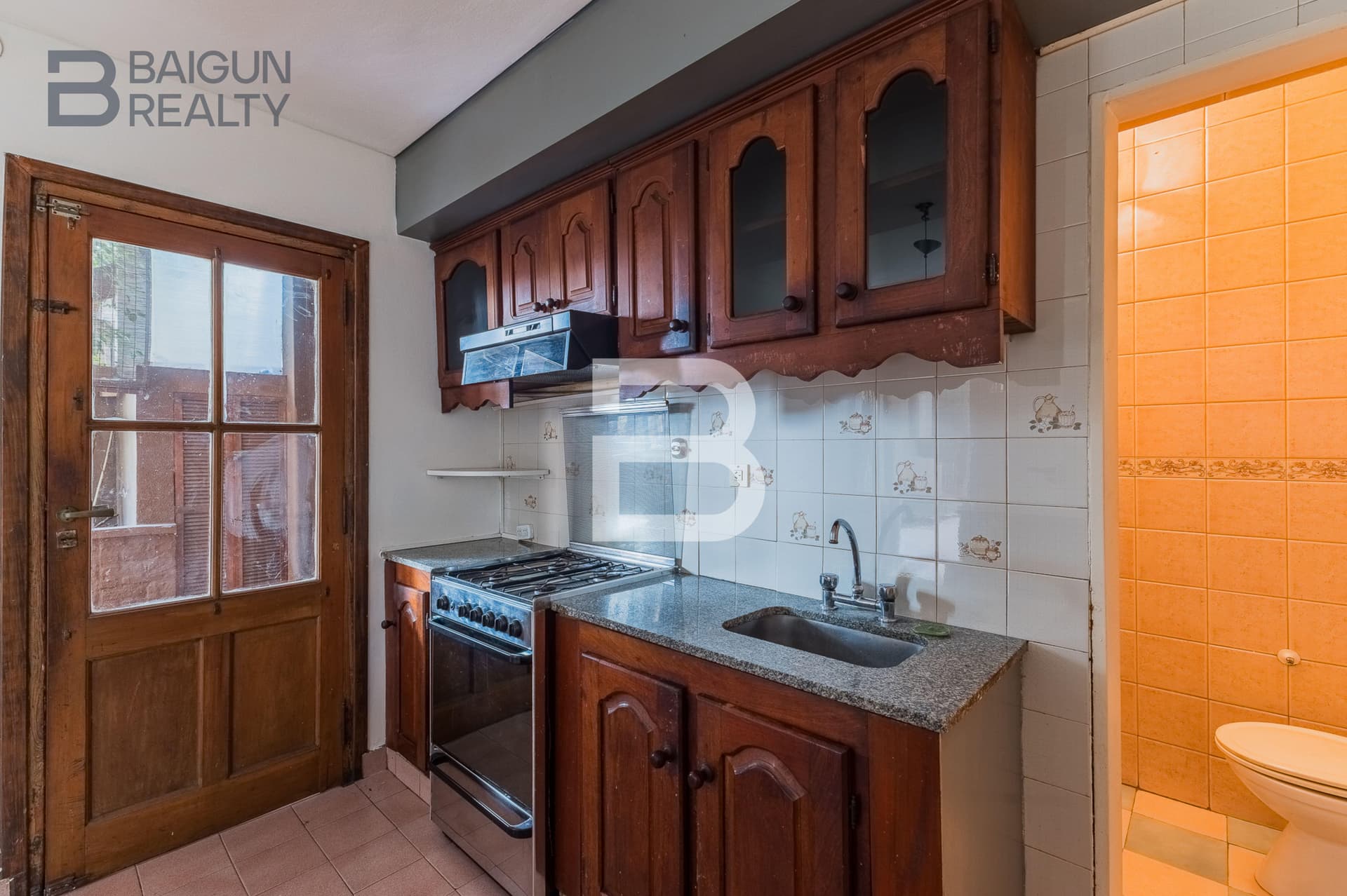 Cocina con bacha, anafe y puerta de madera.