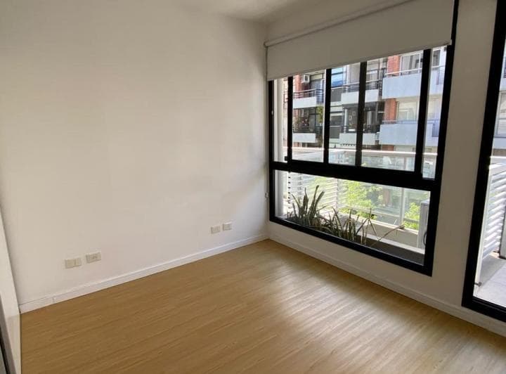 Living vacío con piso de madera y ventana con vista al exterior.
