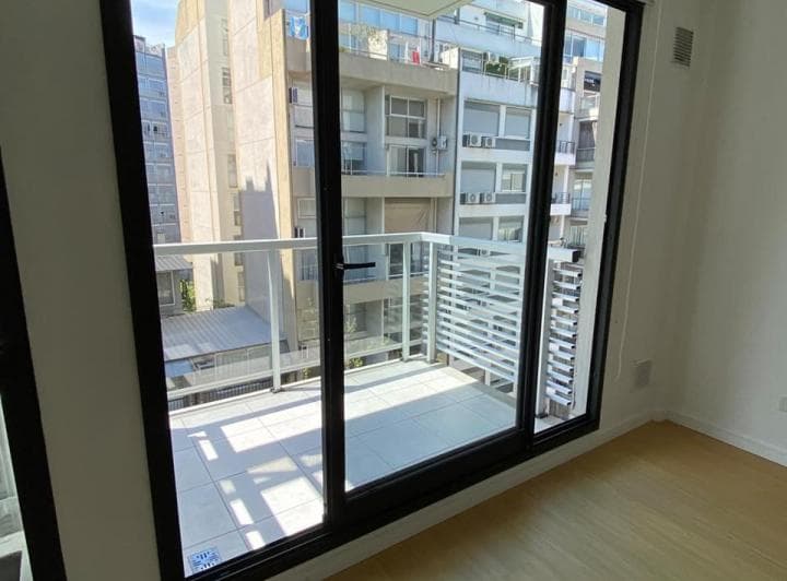 Balcón con vista a edificios desde el interior del departamento.