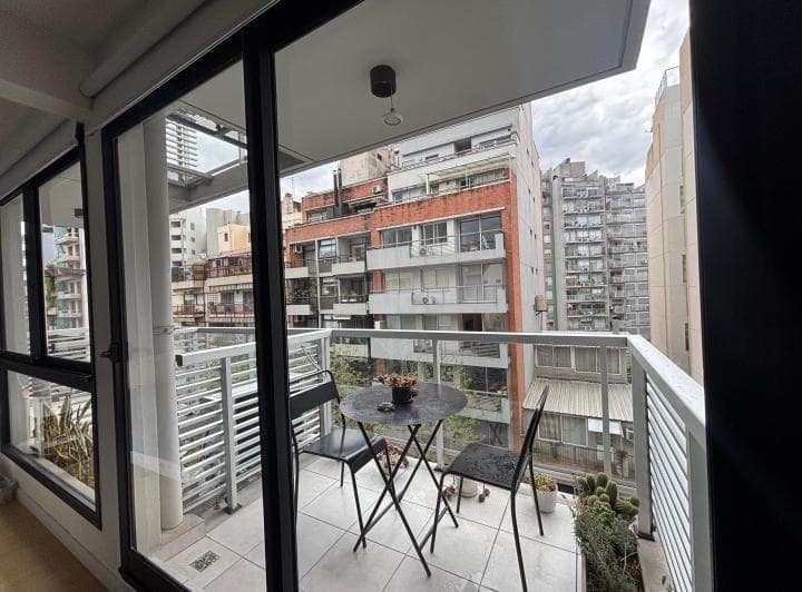 Balcón con mesa y sillas de exterior y vista a edificios.