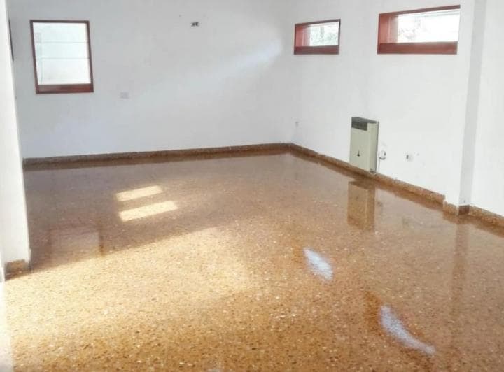 Habitación vacía con piso de granito, estufa y ventanas pequeñas.