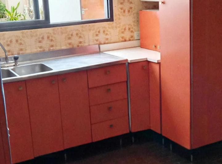 Cocina con mesada, bacha, anafe y muebles de color naranja.