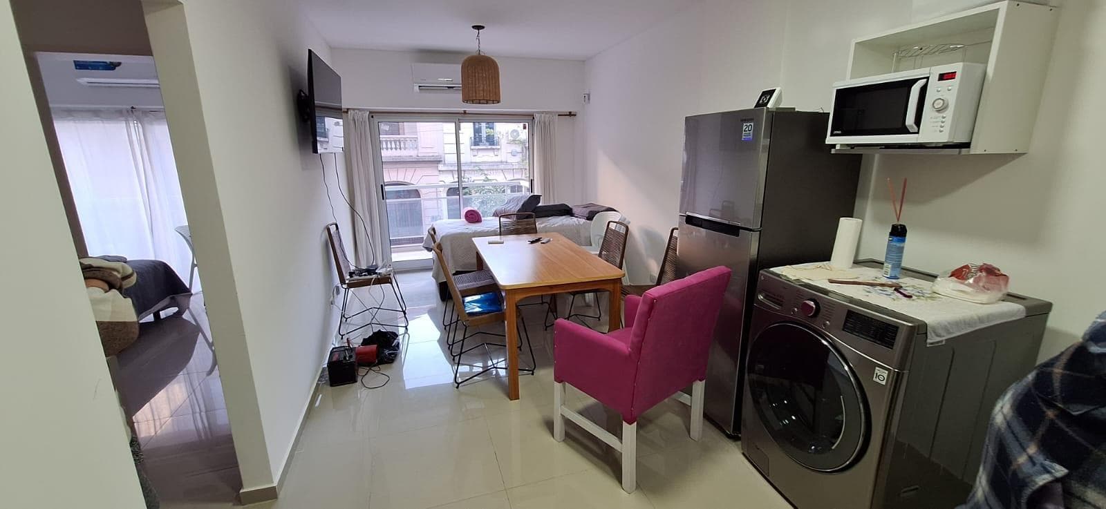 Cocina integrada con lavarropas, microondas, y comedor al fondo.