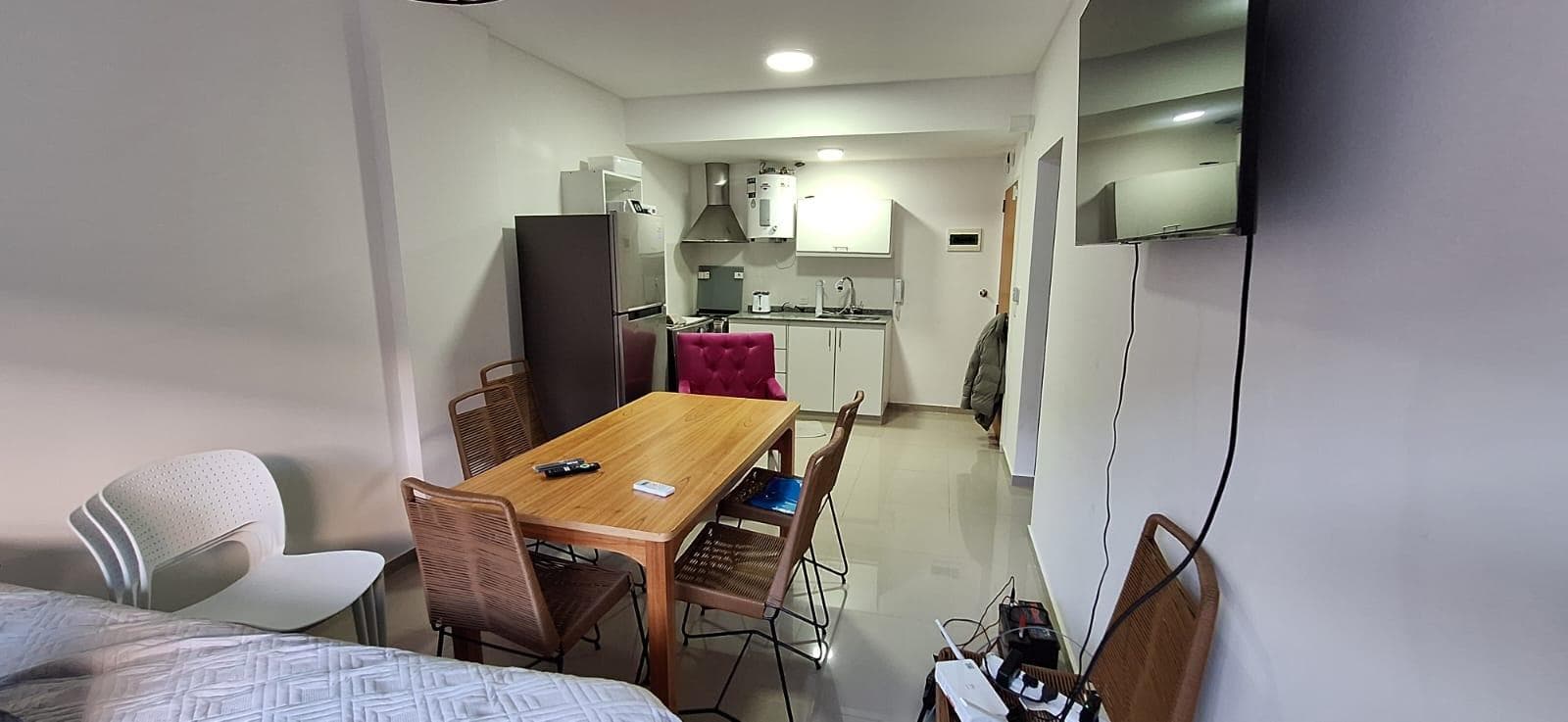 Living-comedor con mesa de madera, sillas y cocina integrada.