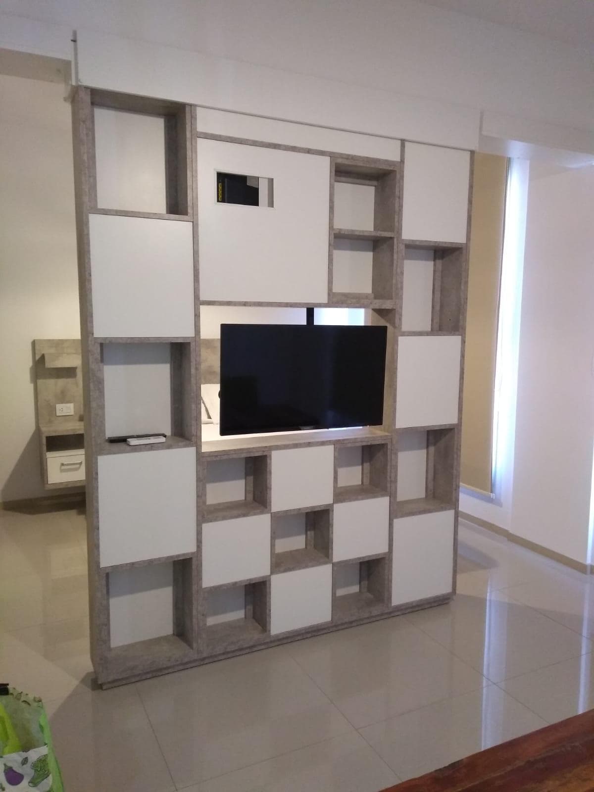 Living con mueble divisor moderno y televisor de pantalla plana.